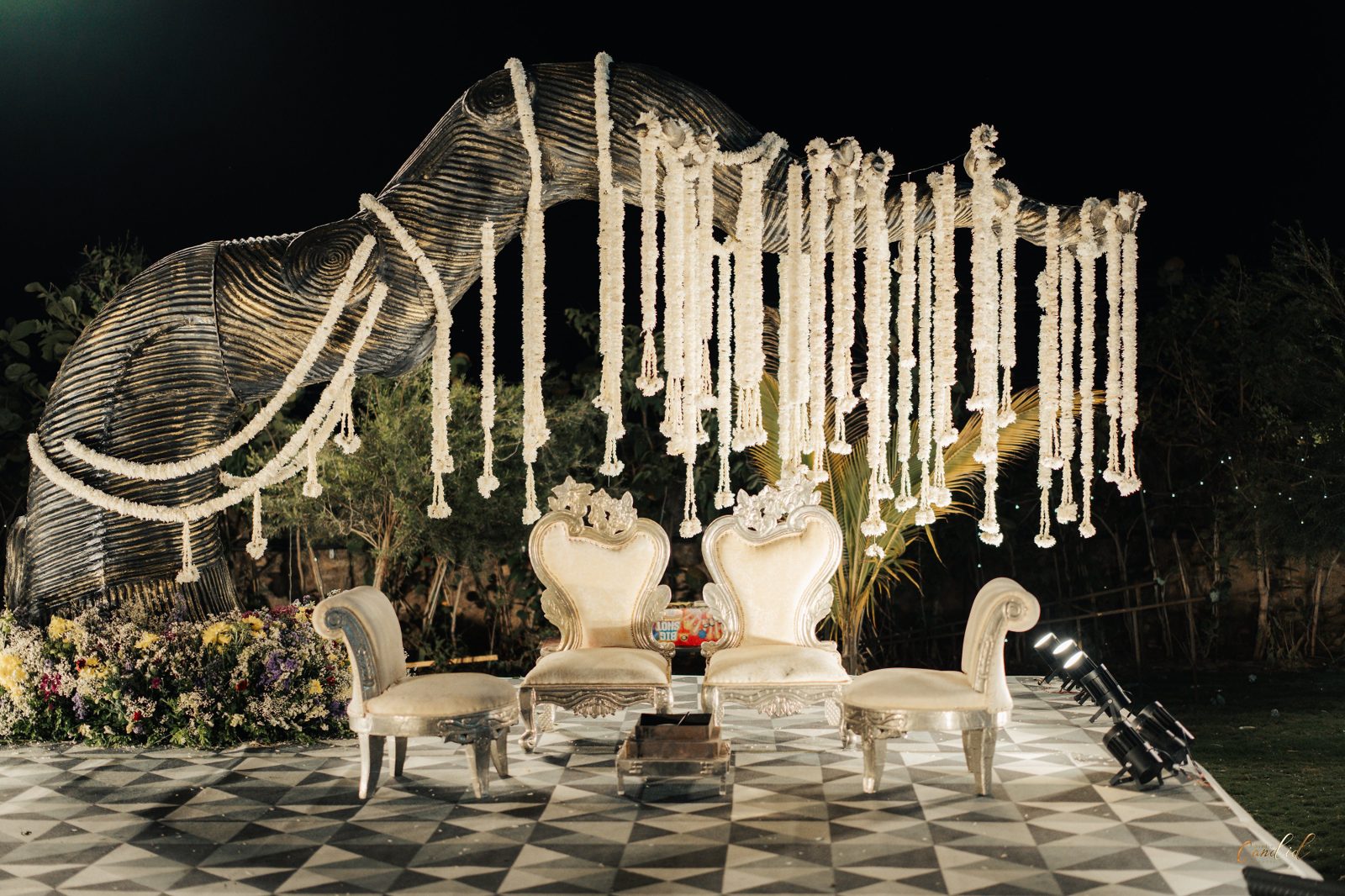 Close-up of the couple's floral-framed throne beneath the elephant centrepiece at night
