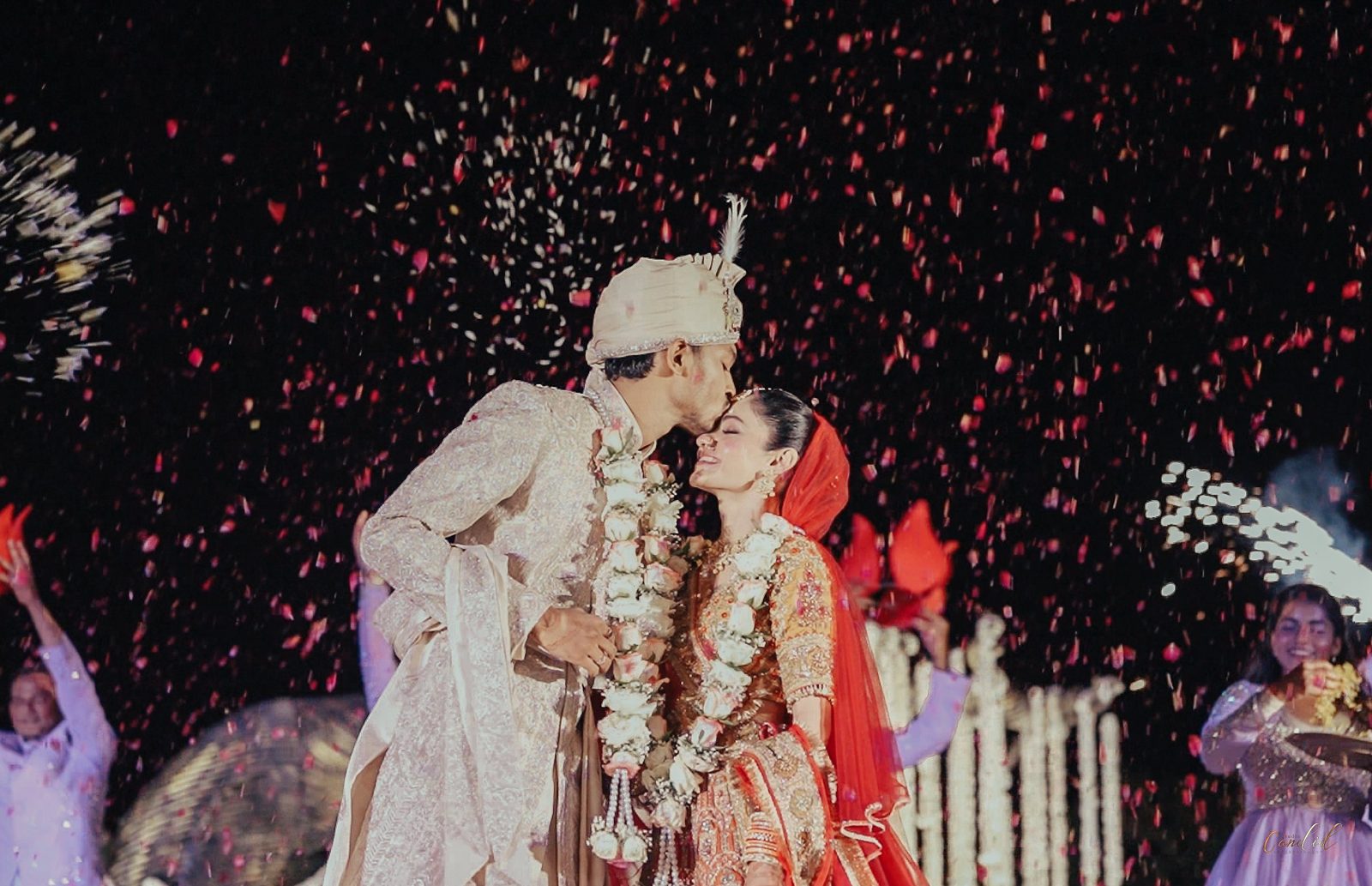 Newlywed couple sharing a kiss under a shower of petals